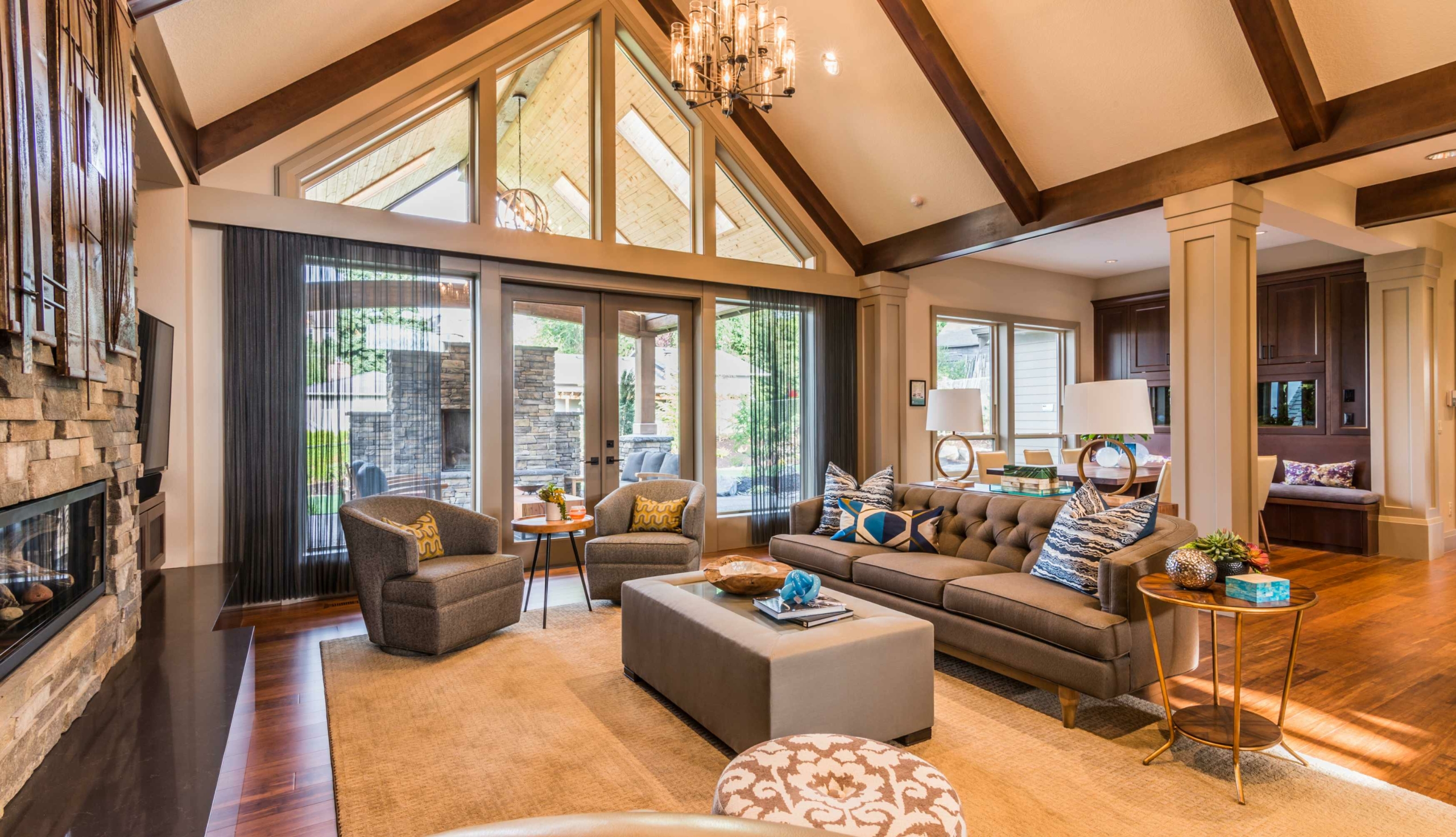 gold updated living room with beamed ceilings and brown area rug.